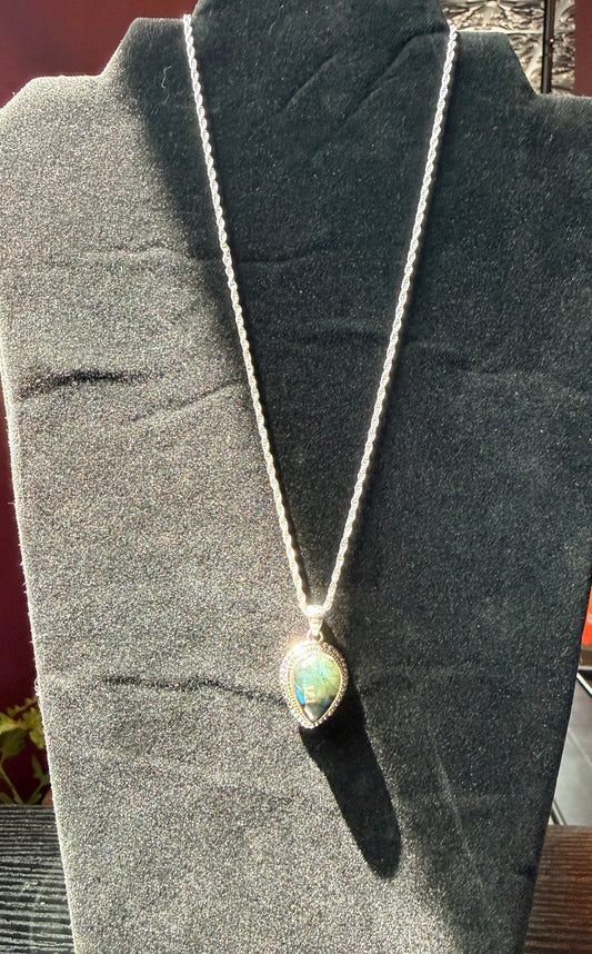 Sterling silver necklace resting on a black velvet jewelry stand holding a labradorite pendant