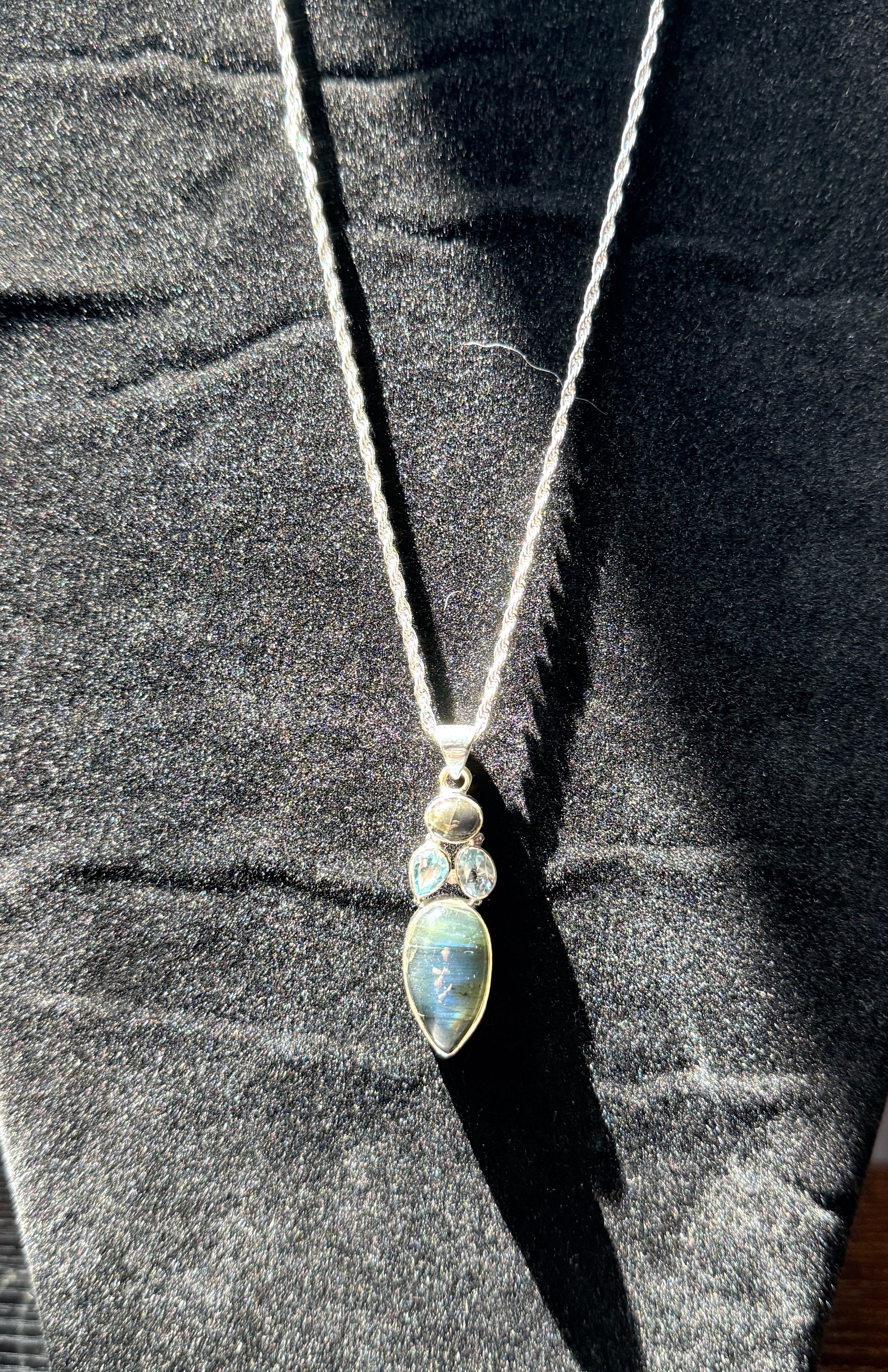 Sterling silver necklace resting on a black velvet jewelry stand holding an ovular labradorite pendant