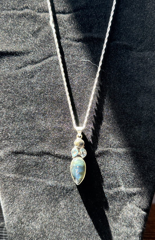 Sterling silver necklace resting on a black velvet jewelry stand holding an ovular labradorite pendant