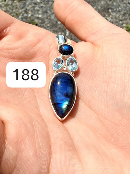 Hand holding a flashing labradorite pendant with two aquamarines set above it in sterling silver