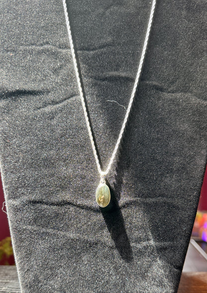 Sterling silver necklace resting on a black velvet jewelry stand holding an ovular labradorite pendant
