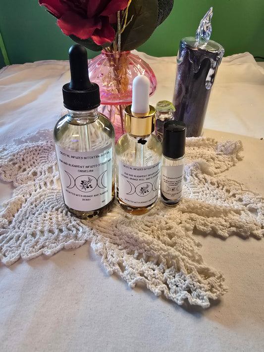 Three glass bottles filled with clear body oil with herbs on a white crochet mat and white table cloth