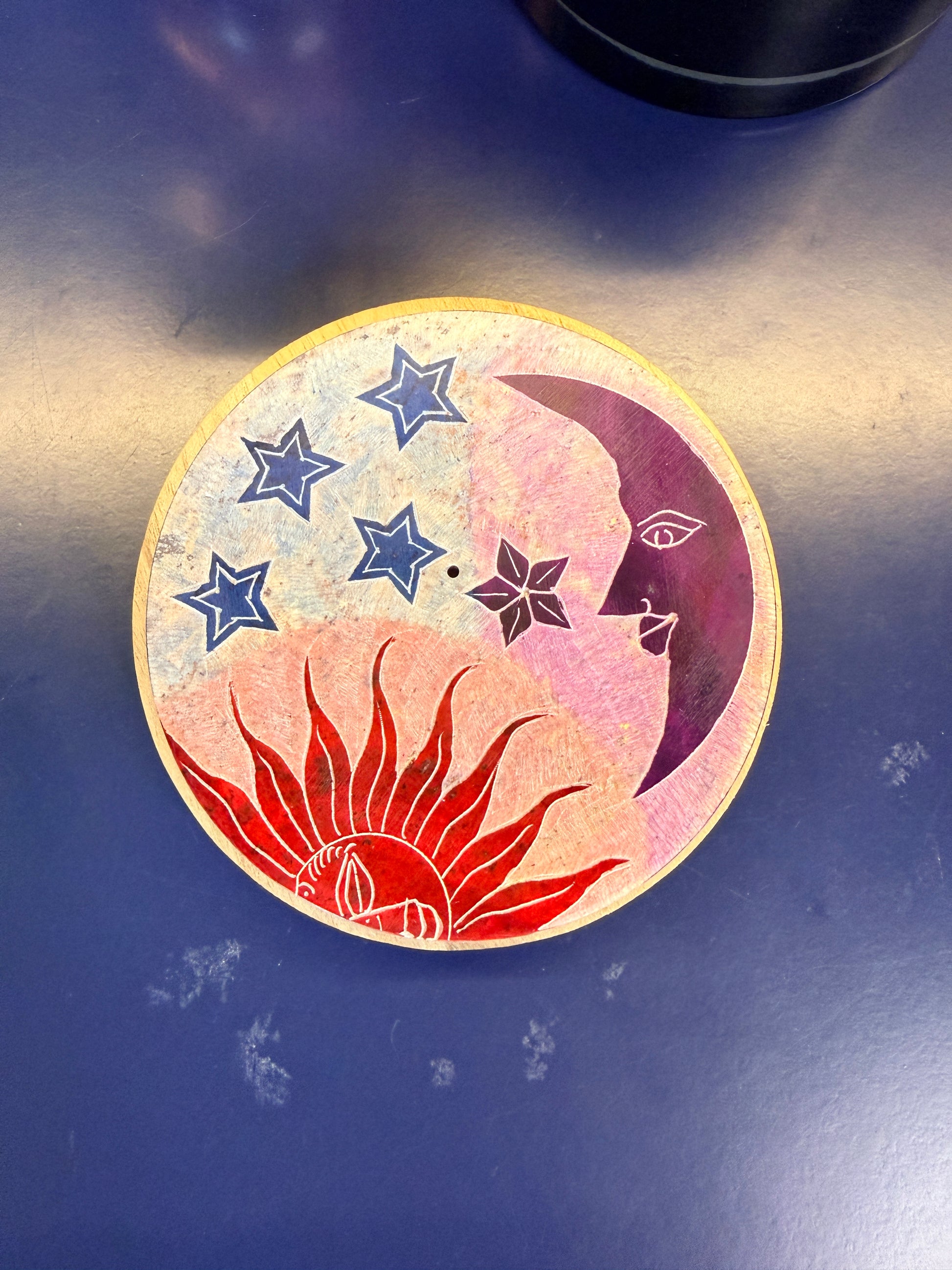 Round incense burner with a sun, star, and moon design on a blue background