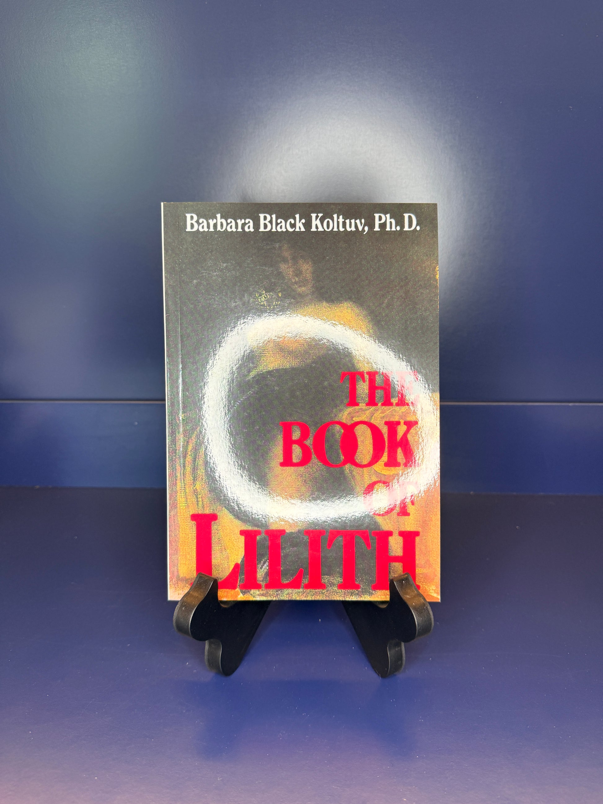 Book titled 'The Book of Lilith' by Barbara Black Koltuv, Ph.D. on a stand against a blue background