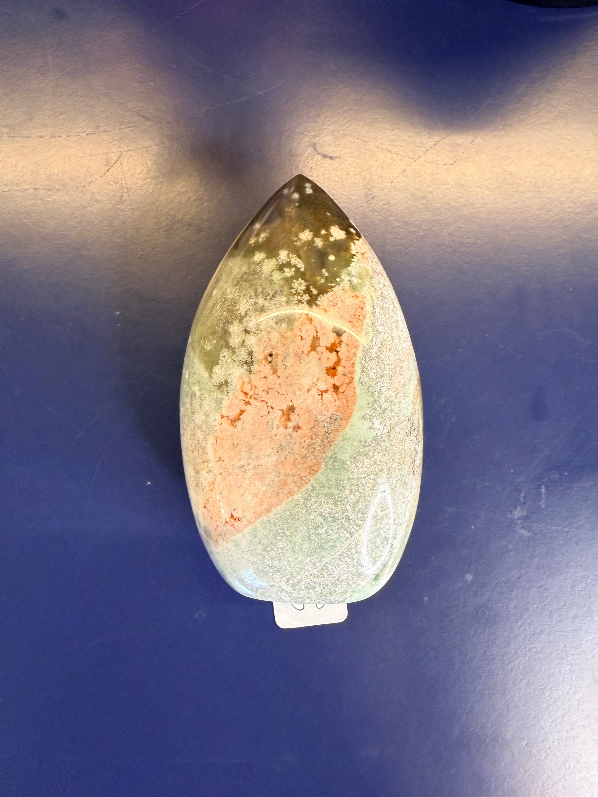  A green, white, and peach unicorn jasper free form on a blue background