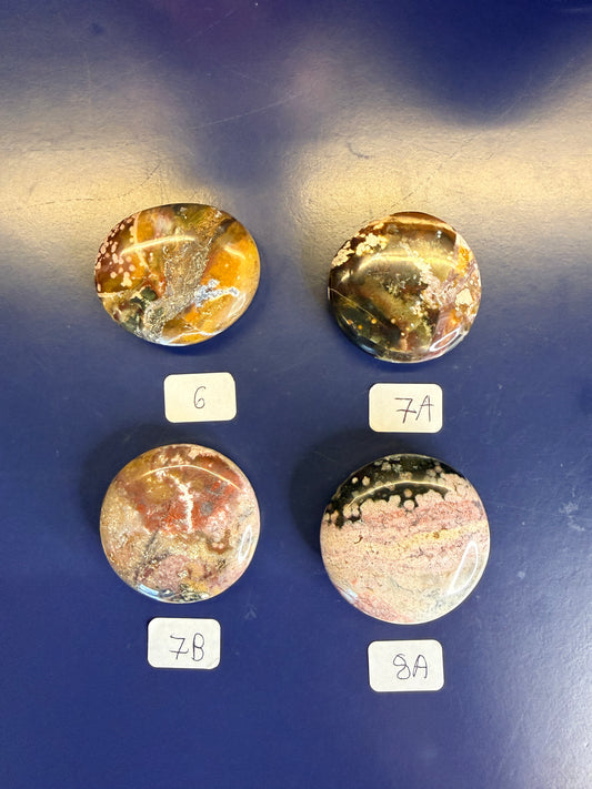 Four multicolored unicorn jasper palmstones with labels on a blue background
