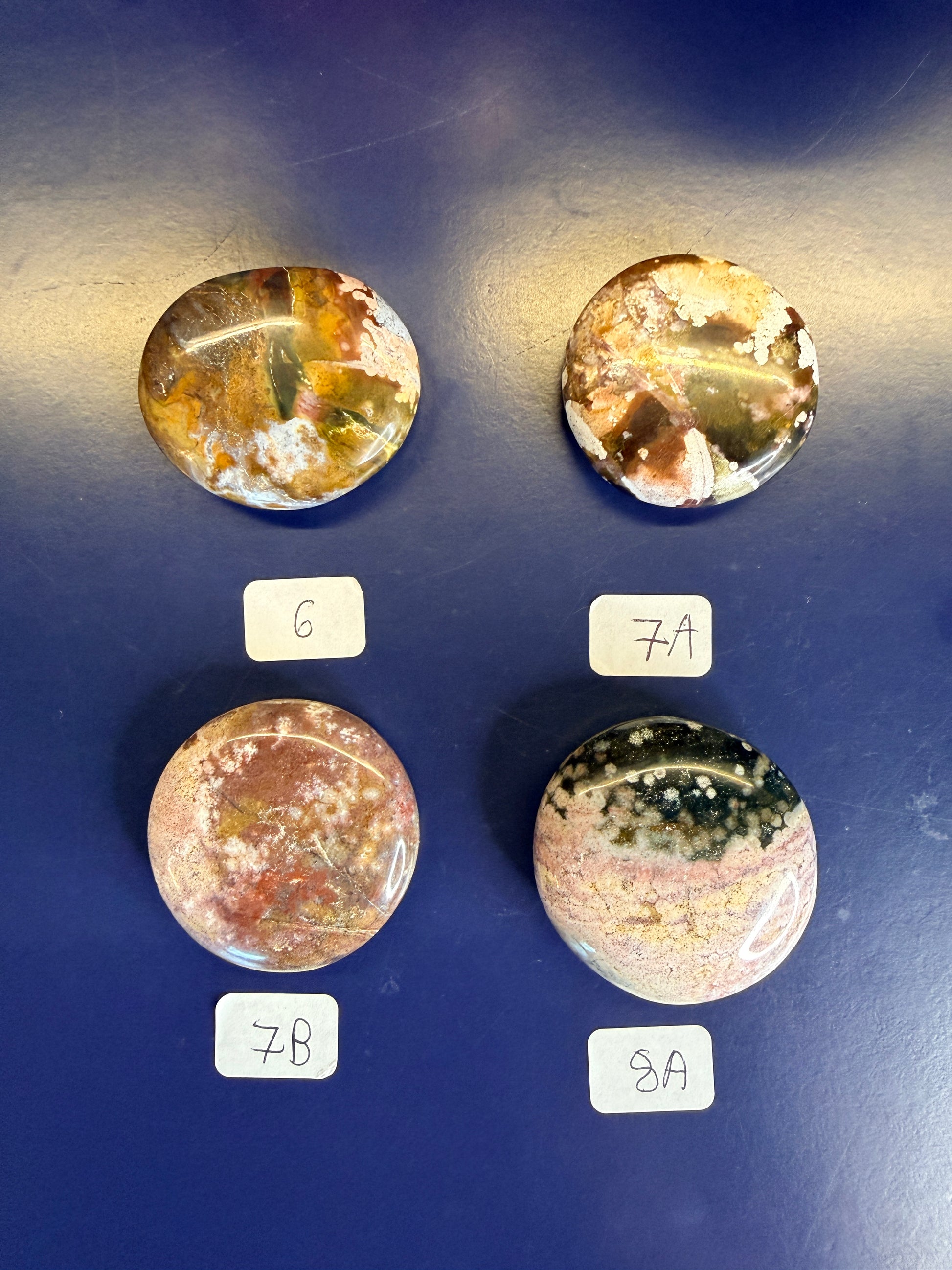 Four multicolored unicorn jasper palmstones with labels on a blue background