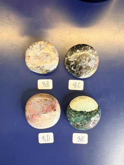 Four multicolored unicorn jasper palmstones with labels on a blue background