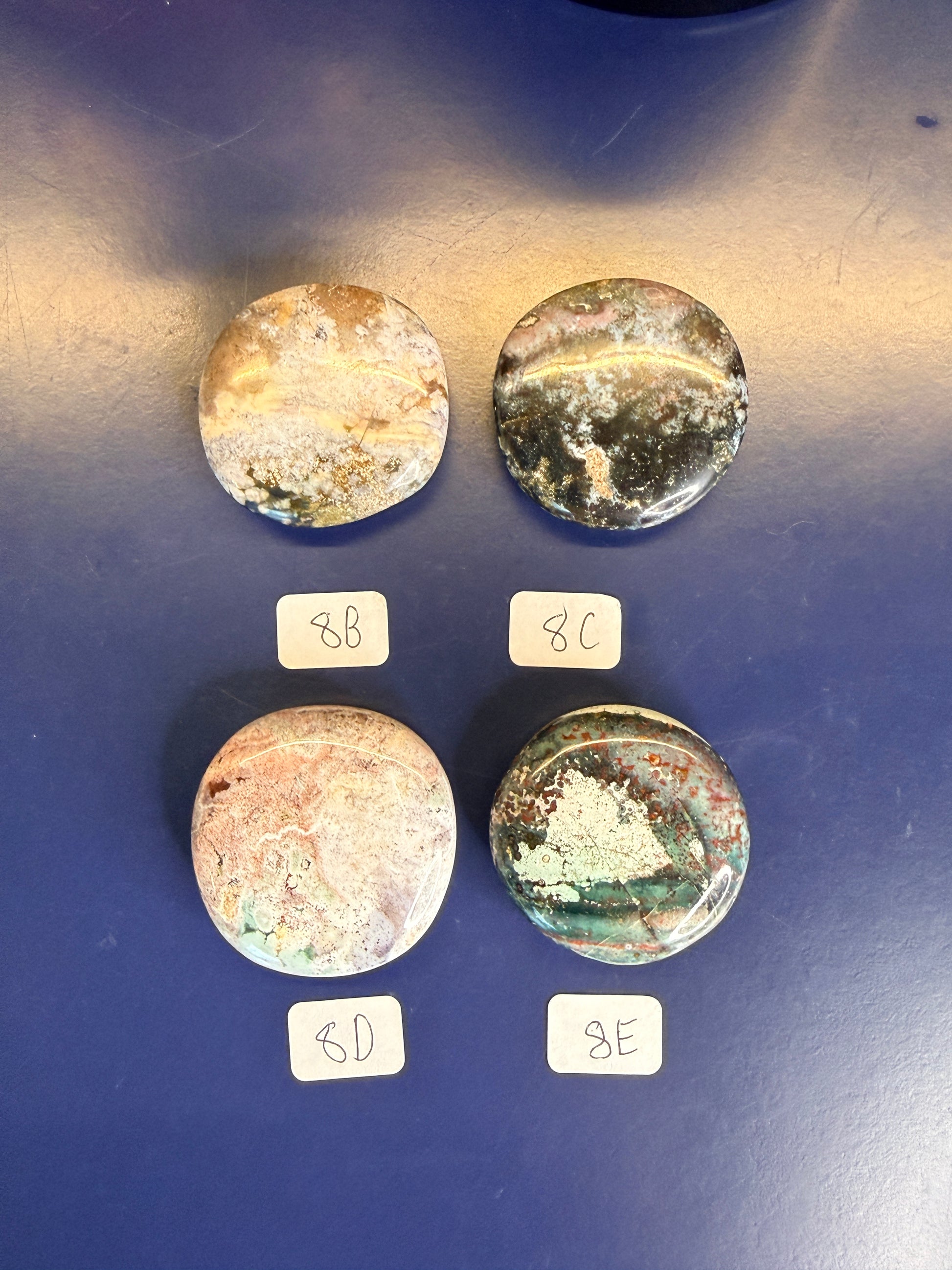 Four multicolored unicorn jasper palmstones with labels on a blue background