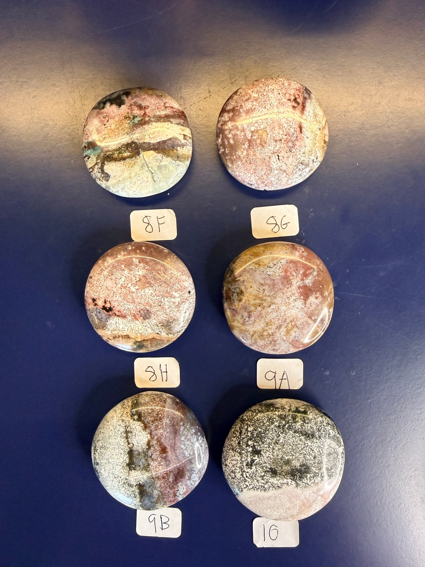 Six multicolored unicorn jasper palmstones with labels on a blue background