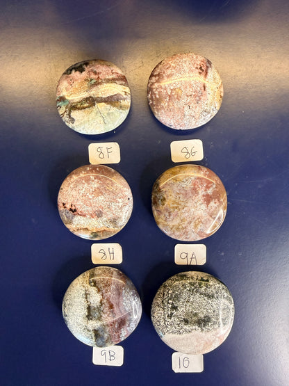 Six multicolored unicorn jasper palmstones with labels on a blue background