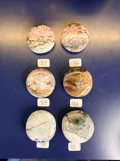Six multicolored unicorn jasper palmstones with labels on a blue background