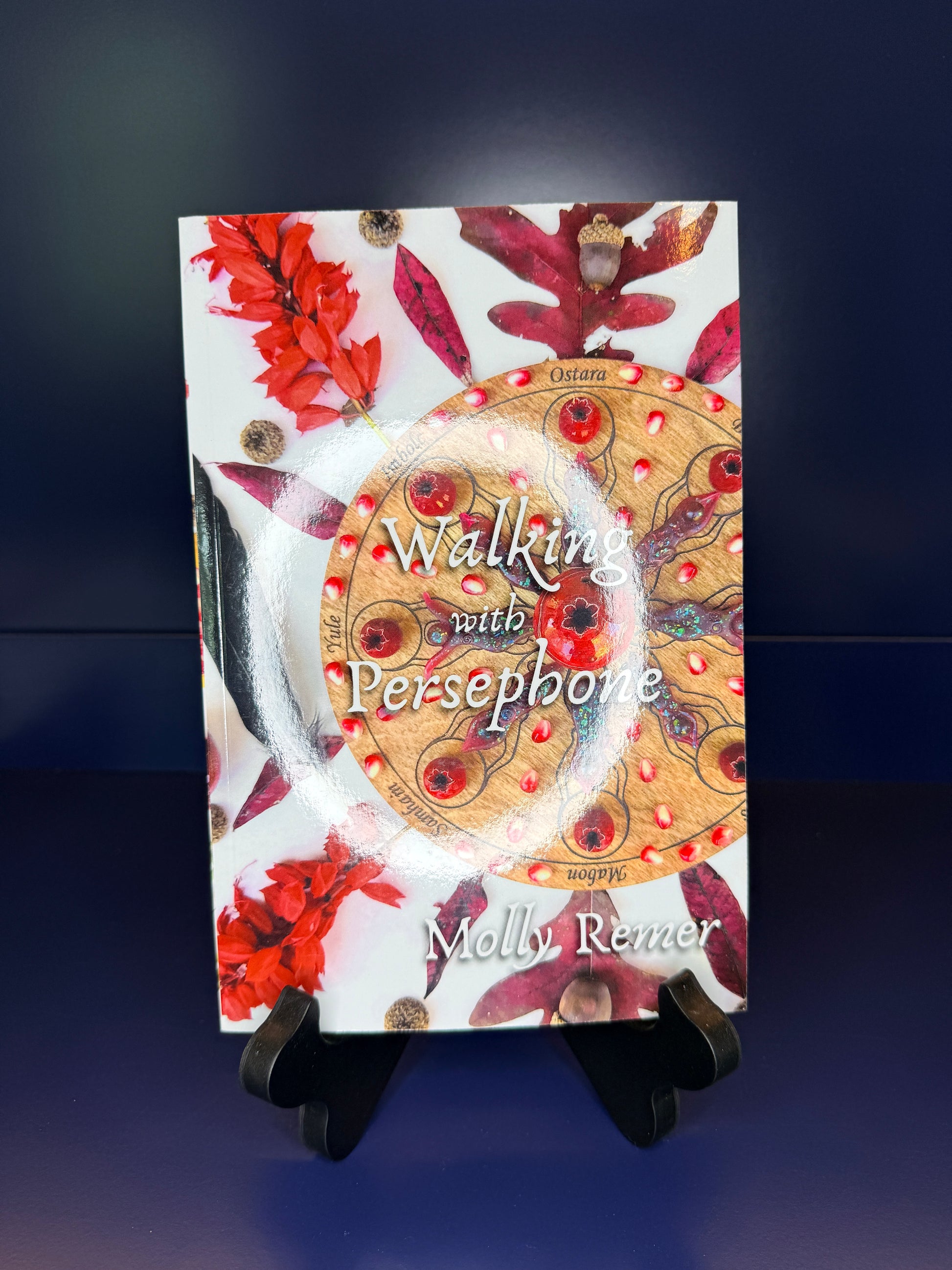 Book titled 'Walking with Persephone' by Molly Reimer on a stand against a dark background