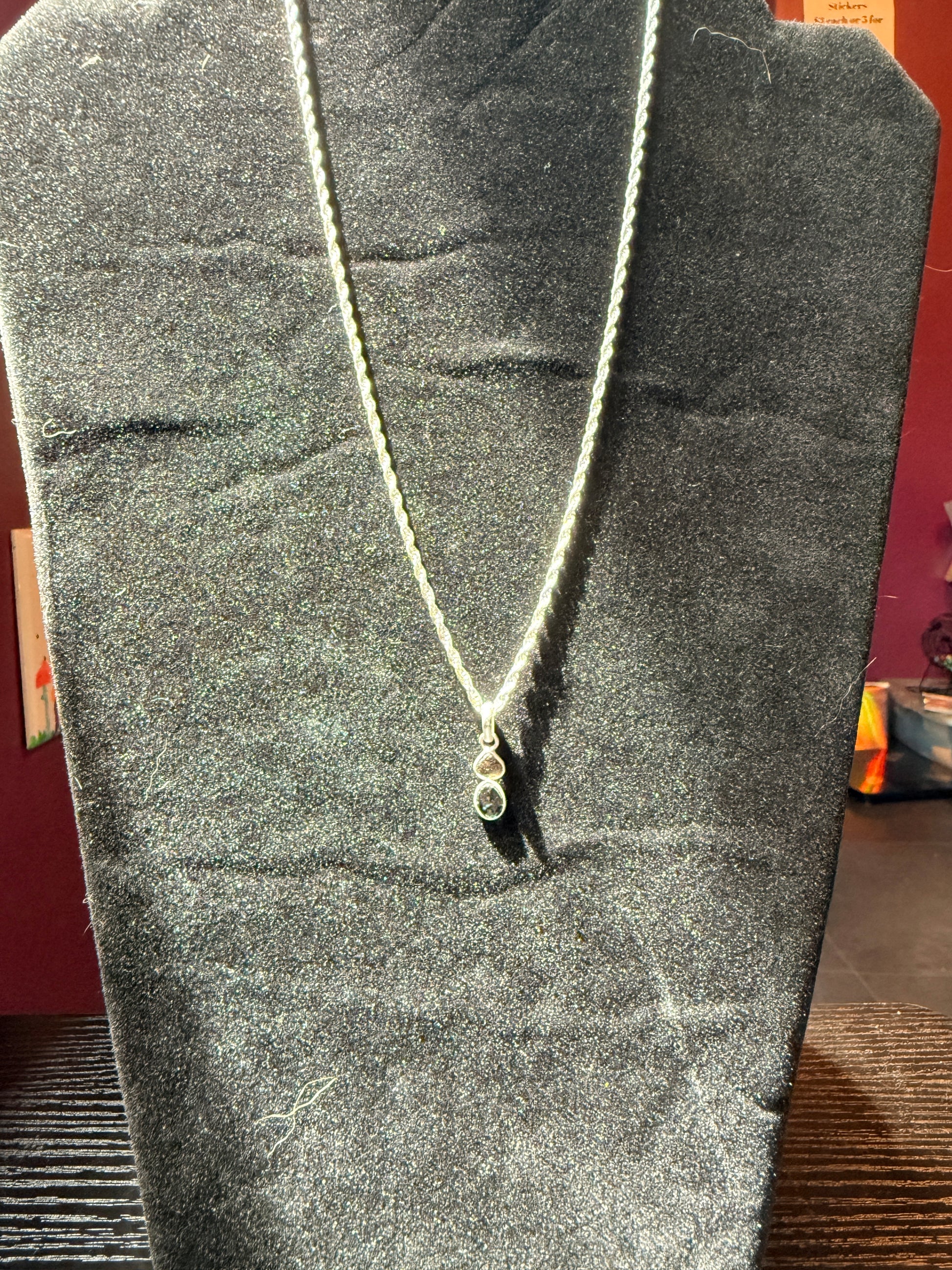 Sterling silver chain resting on a black velvet jewelry stand holding a stacked watermelon tourmaline pendant