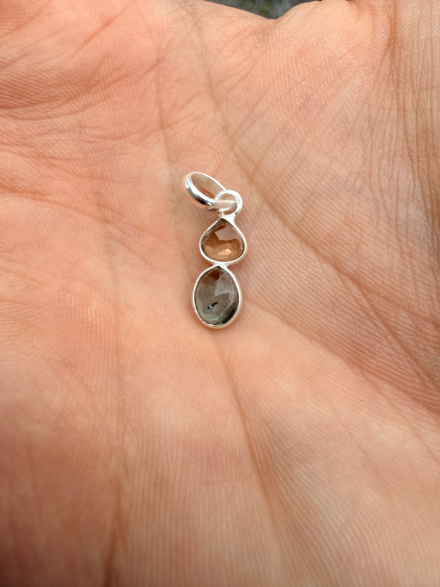 Hand holding a small watermelon tourmaline pendant with two stones 