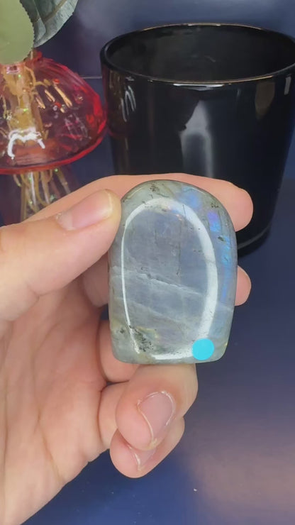 Two hands showing grey labradorite free forms and their purple sunset flash